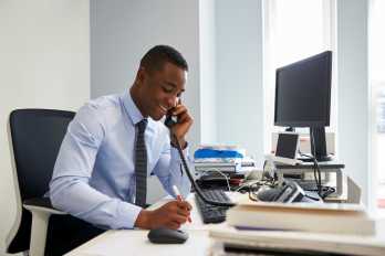 young black businessman using the phone at his office desk